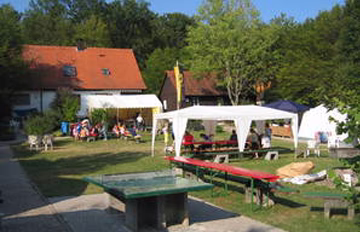 Gartenanlage mit Schwimmbecken und Grill-Catering unter weißen Zelten, um eine Veranstaltung im Freien zu bewirten.