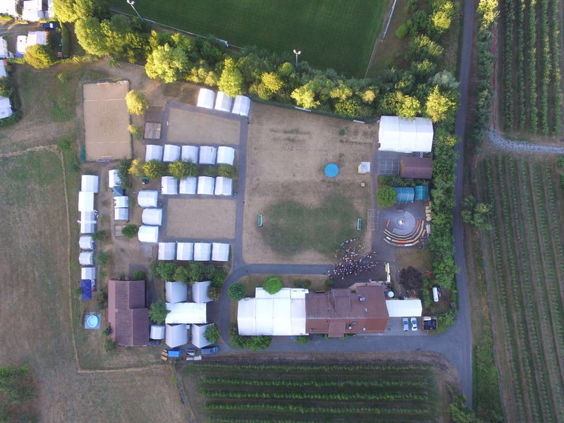 Aerialansicht eines Hofgrundstücks mit Gebäuden, umhaustem Gartenhof, Gehwegen, Wasserbassin und Zufahrtsring.