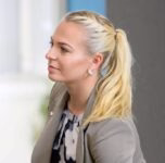 Porträt einer Frau im Profil mit ärztlichem Kittel; Blick zur Seite, wirkt konzentriert, vermittelt medizinische Kompetenz.
