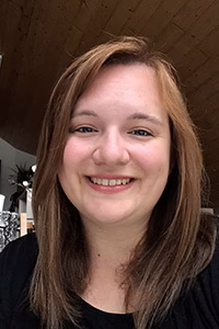 Porträt einer lächelnden Person mit kurzem braunem Haar vor neutralem Hintergrund, geeignet für Team- oder Kontaktseite.